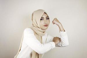 magnifique jeune femme musulmane forte isolée sur un mur de fond blanc montrant des biceps. photo