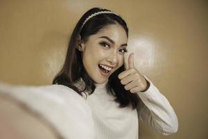 jeune femme asiatique est selfie avec un visage souriant heureux et signe ok près de la bouche regarde la caméra photo