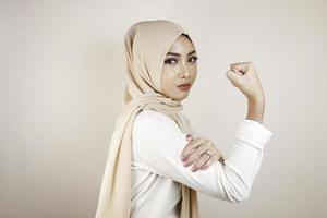 magnifique jeune femme musulmane forte isolée sur un mur de fond blanc montrant des biceps. photo