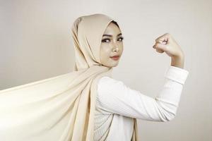 magnifique jeune femme musulmane forte isolée sur un mur de fond blanc montrant des biceps. photo