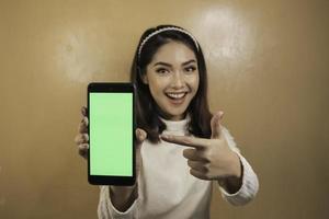jeunes femmes asiatiques heureuses et souriantes montrant un écran blanc vert. photo