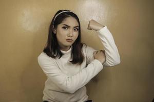 magnifique jeune femme asiatique forte avec une chemise blanche montrant des biceps et souriant. concept fort de fille indonésienne. photo