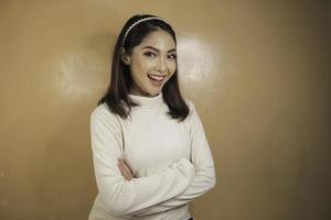 une jeune femme asiatique tient les mains croisées avec un regard sérieux, souriant et confiant. photo