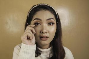 verser des larmes et triste expression d'une jeune femme asiatique en chemise blanche photo