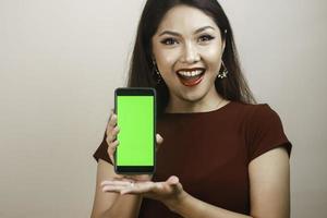 jeune femme asiatique heureuse et souriante montrant et pointant vers un écran blanc vert. photo