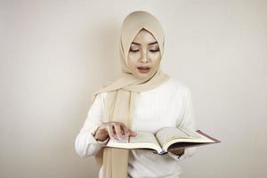 jeune femme musulmane asiatique portant un foulard lisant le coran photo