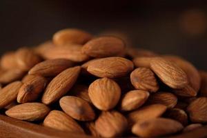 amandes dans un bol en bois sur une table en bois.matière première diététique photo