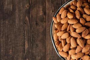 amandes dans un bol en bois sur une table en bois.matière première diététique photo