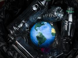 le globe terrestre est jeté dans une poubelle avec des déchets en plastique, le jour de la terre, l'écologie et le concept d'environnement photo