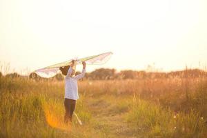 la fille est debout avec des ailes dans le champ, apprenant à faire voler un cerf-volant. animations de plein air en été, nature et grand air. l'enfance, la liberté et l'insouciance. les rêves et l'espoir des enfants photo