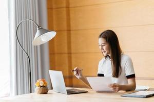 jeune femme souriante utilisant un ordinateur portable, assise sur un canapé à la maison, belle fille faisant du shopping ou discutant en ligne sur un réseau social, s'amusant, regardant un film, pigiste travaillant sur un projet informatique photo