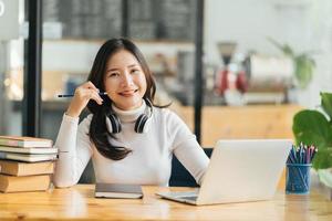 heureuse jeune femme asiatique agitant la main parlant avec un professeur de web à distance sur la classe d'apprentissage en ligne par vidéoconférence à distance sociale sur ordinateur. fille qui apprend à la maison photo