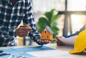 architecte et ingénieur planifiant une réunion pour un nouveau projet avec des équipements de construction sur table, architecte et ingénieur travaillant avec un plan et un modèle de maison. photo