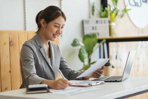 portrait d'une charmante fille joyeuse et concentrée réussie travaillant à distance créant un rapport de présentation des finances à la maison à l'intérieur photo