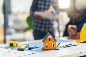 architecte et ingénieur planifiant une réunion pour un nouveau projet avec des équipements de construction sur table, architecte et ingénieur travaillant avec un plan et un modèle de maison. photo