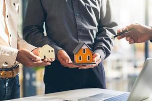 modèle de maison avec agent et client discutant d'un contrat d'achat, d'assurance ou de prêt d'un bien immobilier ou d'une propriété. photo