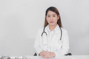 femme médecin asiatique regardant droit à l'hôpital portant un manteau blanc et un stéthoscope sur un concept de soins de santé de fond blanc. photo