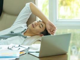 jeune homme d'affaires asiatique fatigué et endormi après avoir trouvé des informations sur internet, à utiliser dans la concurrence commerciale photo