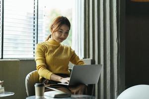 portrait d'une belle femme asiatique assise à l'intérieur au café-restaurant pendant l'été, à l'aide d'un ordinateur portable et d'un smartphone à technologie sans fil intelligente, pause-café relaxante au café-restaurant. photo