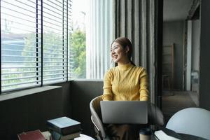 portrait d'une belle femme asiatique assise à l'intérieur au café-restaurant pendant l'été, à l'aide d'un ordinateur portable et d'un smartphone à technologie sans fil intelligente, pause-café relaxante au café-restaurant. photo