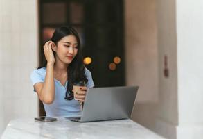 belle jeune femme d'affaires asiatique mignonne dans le café, à l'aide d'un ordinateur portable. photo