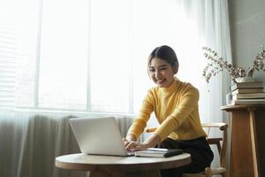 portrait d'une belle femme asiatique assise à l'intérieur au café-restaurant pendant l'été, à l'aide d'un ordinateur portable et d'un smartphone à technologie sans fil intelligente, pause-café relaxante au café-restaurant. photo