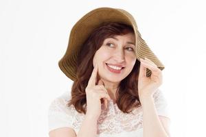 femme heureuse au chapeau d'été isolé sur fond blanc. protection solaire soins de la peau et concept de vacances vacances. femme d'âge moyen avec des dents blanches et saines et ménopause. vacances de voyage. copie espace photo