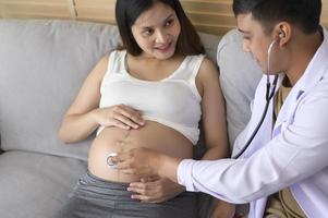 un médecin tenant un stéthoscope examine une femme enceinte à l'hôpital, les soins de santé et le concept de soins de grossesse photo