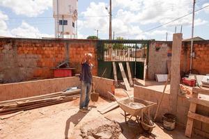 planaltina goias, brésil, 16 avril 2022 un homme mélangeant du ciment avec une pelle à utiliser pour poser des briques. photo