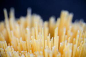 longs spaghettis jaunes sur fond rustique. pâtes italiennes jaunes. longs spaghettis. spaghettis crus à la bolognaise. spaghettis crus. concept de fond de nourriture. concept de cuisine et de menu italien. photo