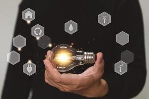 main tenant l'ampoule. idée avec environnement et innovation. technologie innovante et concept de conception d'entreprise créative de solution.