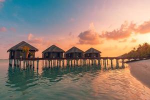 magnifique panorama de coucher de soleil aux maldives. Paysage marin de villas de villégiature de luxe avec des lumières LED douces sous un ciel coloré. beau ciel crépusculaire et nuages colorés. beau fond de plage pour les vacances de vacances photo
