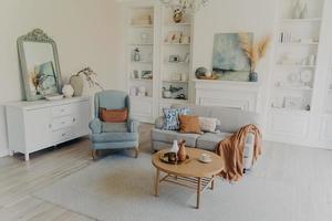 maison moderne ou chambre d'hôtel confortable. canapé et fauteuil, miroir sur coffre, décoration et textile. photo