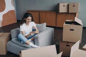 jeune femme espagnole publiant des nouvelles. heureux acheteur d'appartement déballant des boîtes. photo