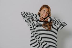 Tourné jusqu'à la taille d'une jeune femme heureuse garde les yeux fermés sourit montre doucement les dents photo