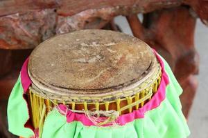 surface ronde du vieux tambour étroit et haut, rayures sur le tambour et couverture en tissu vert à côté, thaïlande. photo