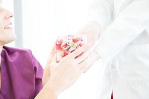 médecin donnant une boîte-cadeau au patient en fauteuil roulant. photo