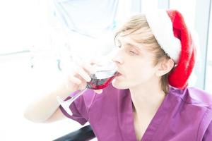 patient masculin buvant du vin pour fêter noël ou le nouvel an. photo