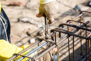 le travailleur utilise du fil et des pinces pour attacher la barre d'armature. photo