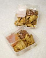 poulet enveloppé d'épices indonésiennes. les morceaux de poulet sont prêts à être frits. aliments prêts à manger dans un emballage complet avec sauce chili, etc. boîte de maquette d'emballage alimentaire pour modèle. flou de mise au point. photo