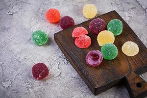 marmelade colorée sur une planche à découper en bois. délicieuses boules de jujube. photo