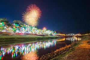 feux d'artifice au bord de l'eau avec des lumières à phitsanulok, thaïlande. photo