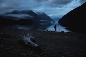 personne au bord d'un lac la nuit photo