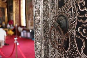 l'ancien bouton de porte en fer de style indigène est sur l'ancienne porte d'art indigène thaïlandaise de l'église du temple, bangkok, thaïlande. photo