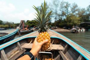 ananas d'été, ananas à la main sur un bateau en mer photo
