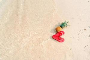 vacances d'été à la plage avec des ananas et des tongs sur la plage photo