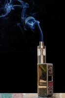 Cigarette électronique 3d et fumée sur la table rock sur fond noir. photo