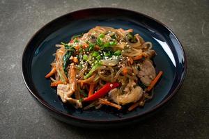 nouilles japchae ou vermicelles coréennes sautées aux légumes et au porc garnies de sésame blanc photo