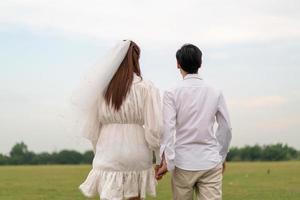 heureux jeune couple asiatique en vêtements de mariée et de marié photo