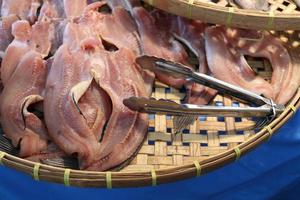 les poissons à tête de serpent rayés séchés au soleil sont sur un panier de vannage de riz et des pinces en acier inoxydable, en thaïlande. photo